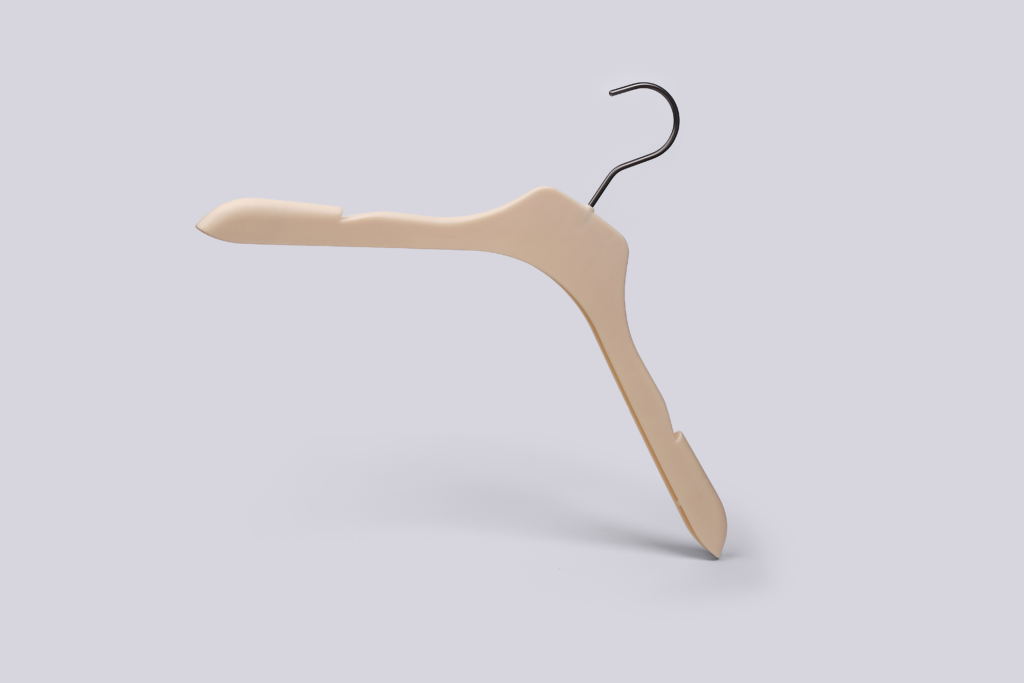 Hangers of London A beige plastic clothes hanger with a metal hook is standing upright on one end against a plain light grey background. The hanger has a modern, slightly angular design.